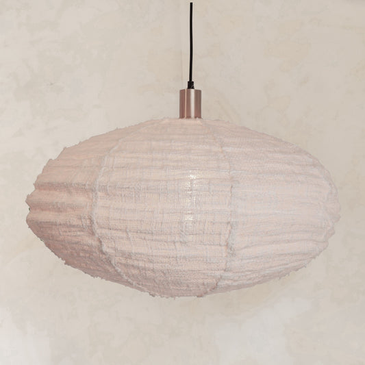 A white, oval-shaped ceiling lampshade made of kapok fabric, with a brass accent on the hanging cord on a neutral background wall by TESUU